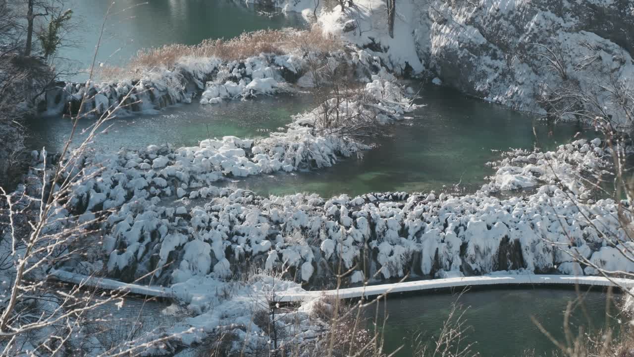 Plitvicemeren, Kroatië, handheld beeldmateriaal van meren en stromend water omgeven door een besneeuwd winterlandschap. Natuurlijk licht, koude seizoenssfeer