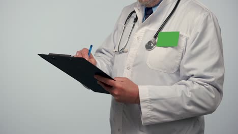 médico masculino toma notas sobre un historial médico o registra su investigación en una carpeta negra. doctor en bata médica blanca con insignia con llave de croma de pantalla verde. cerrar. cámara lenta
