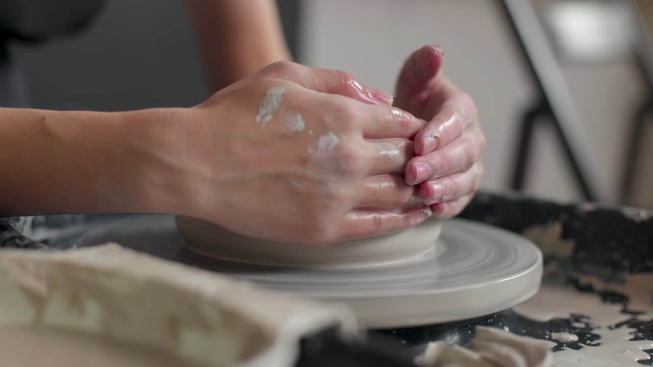 las manos de un maestro alfarero trabajando en una rueda de alfarero, formando un cuenco de arcilla. primer plano, cámara lenta