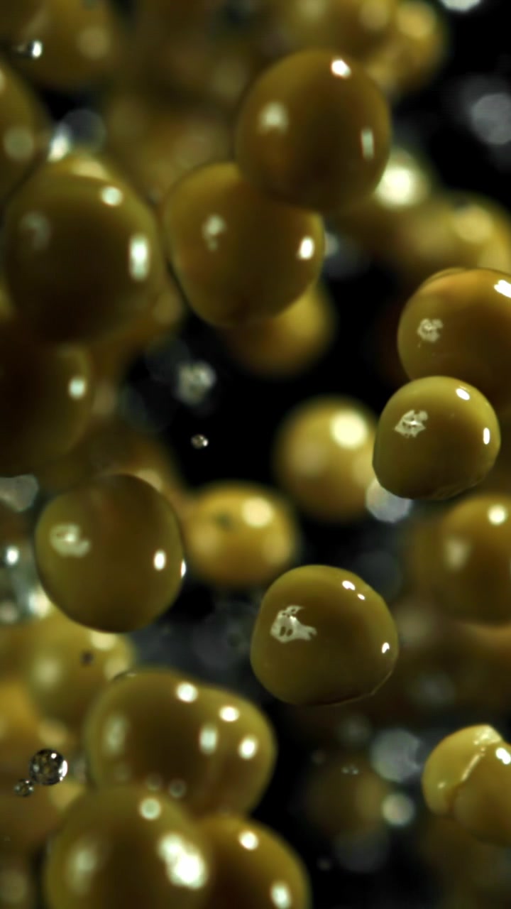 Piselli verdi che galleggiano con bolle d'acqua al rallentatore