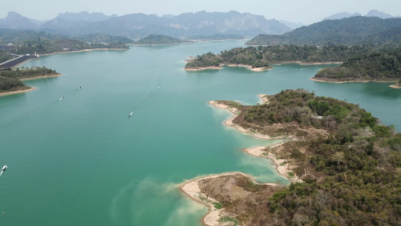 Aerial View of a Serene Turquoise Lake with Lush Islands and Boats Amidst Mountains