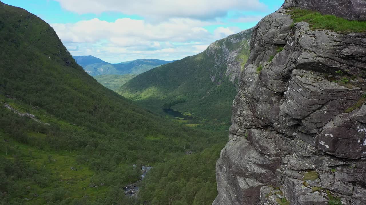 volando suavemente cerca del acantilado con un hermoso valle verde y exuberante en el fondo - antena en movimiento hacia adelante en oyadalen stamnes noruega - desierto completo