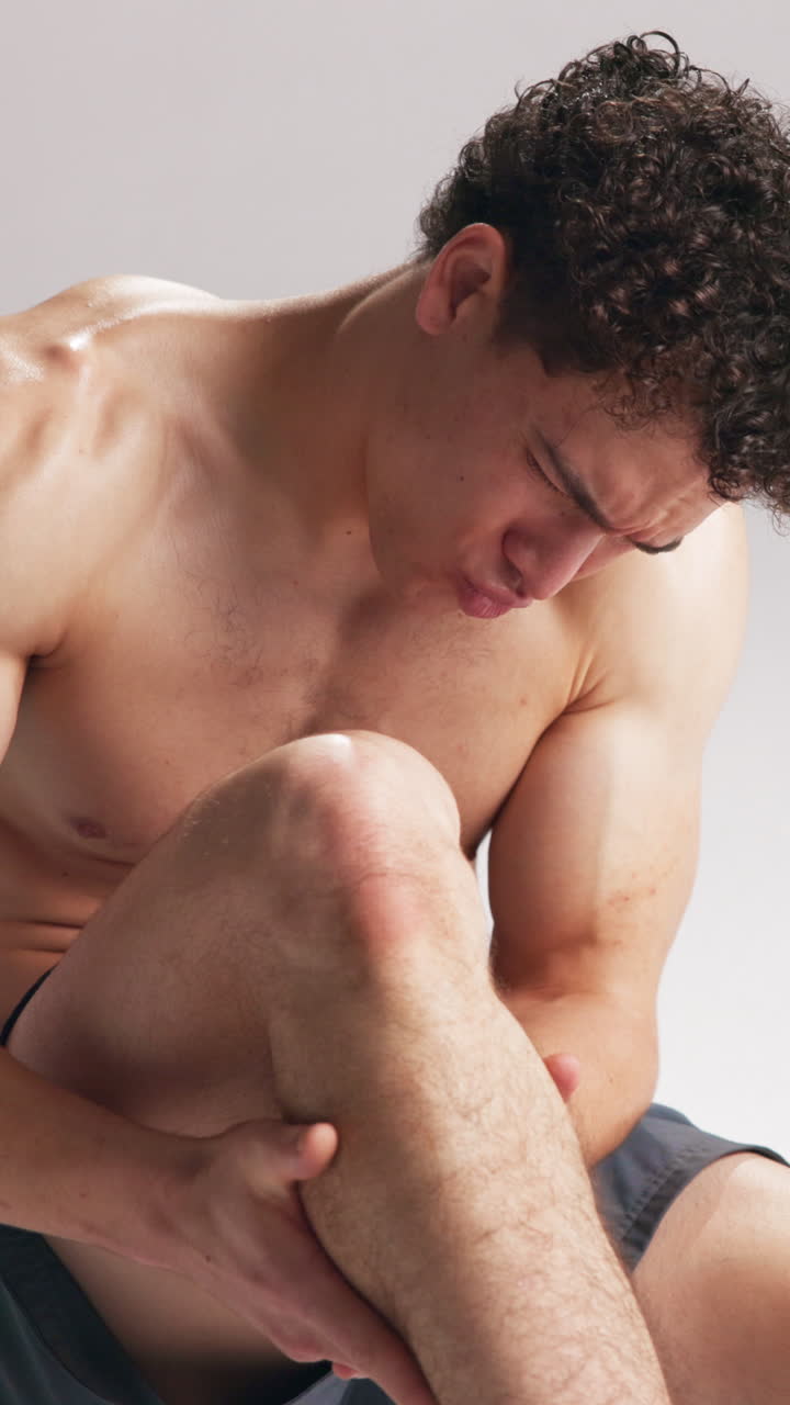Giovane uomo che fa una smorfia di dolore mentre si massaggia la gamba