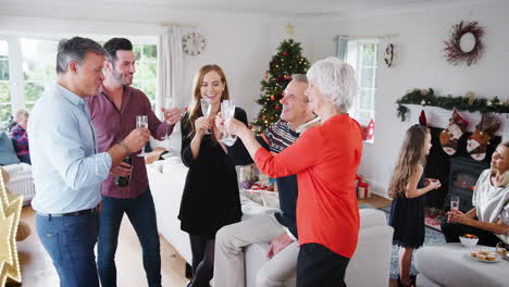 familia y amigos de varias generaciones haciendo un brindis con champán en la fiesta de la casa de navidad