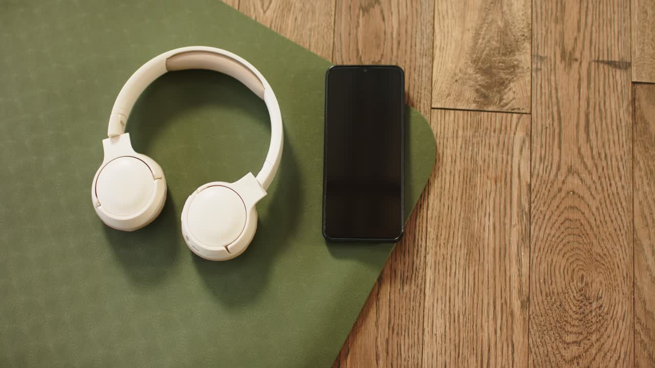 All'inizio della ripresa, cuffie e smartphone sono appoggiati su un tappetino da ginnastica, mettendo in mostra attrezzatura da fitness.