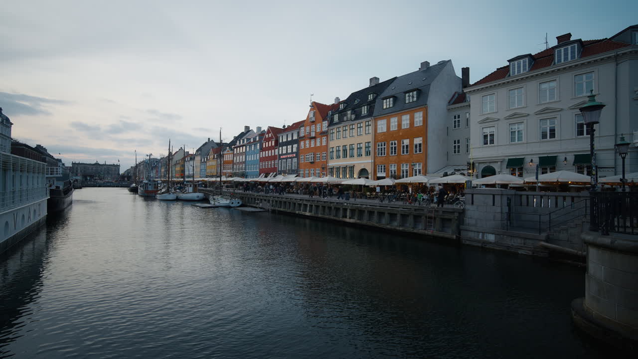 Bredt statisk skud af Nyhavns havn i København tidlig morgen, farverige bygninger langs vandet reflekteret i det rolige vand del 2