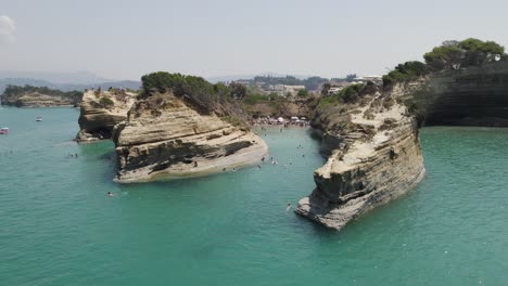 aerial of tourists swimming at sidari beach - terraced cliffs at canal d'amour