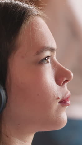 woman listens to podcast via headphones in library premise. young female student thoughtfully looks away sitting by bookcase. leisure in campus