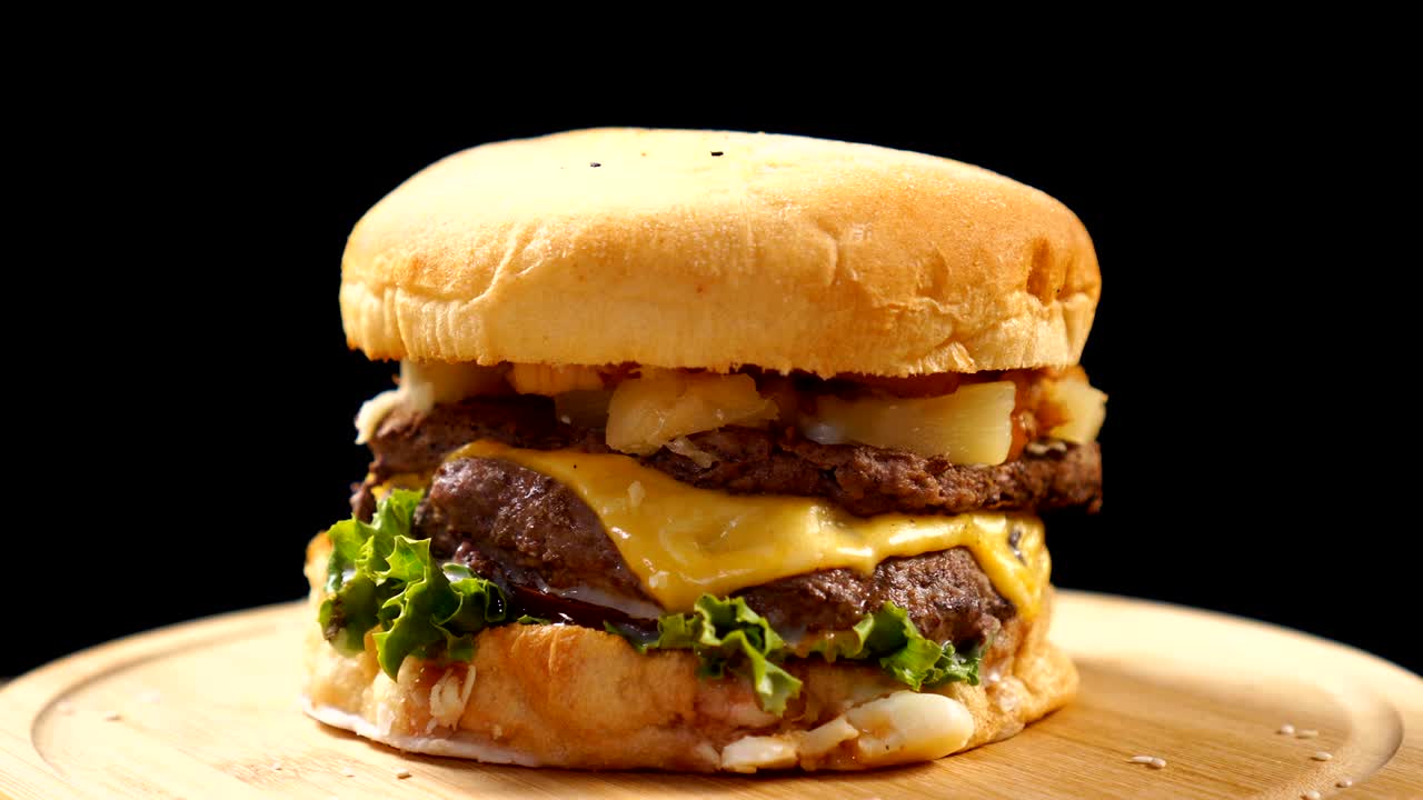 una hamburguesa jugosa de carne está girando rápidamente en la mesa sobre un fondo negro.