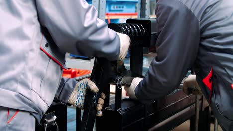 workers fixing black spring shock absorber into machine for processing