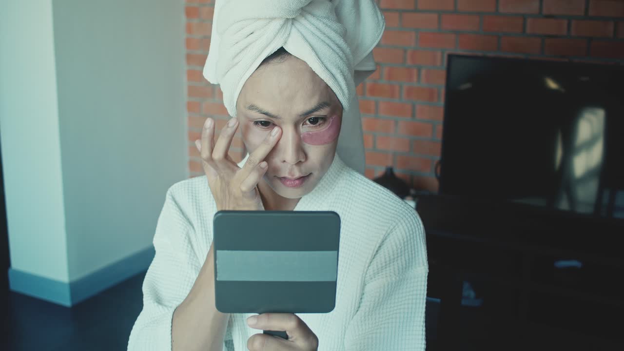 Woman applying eye patches in front of a mirror