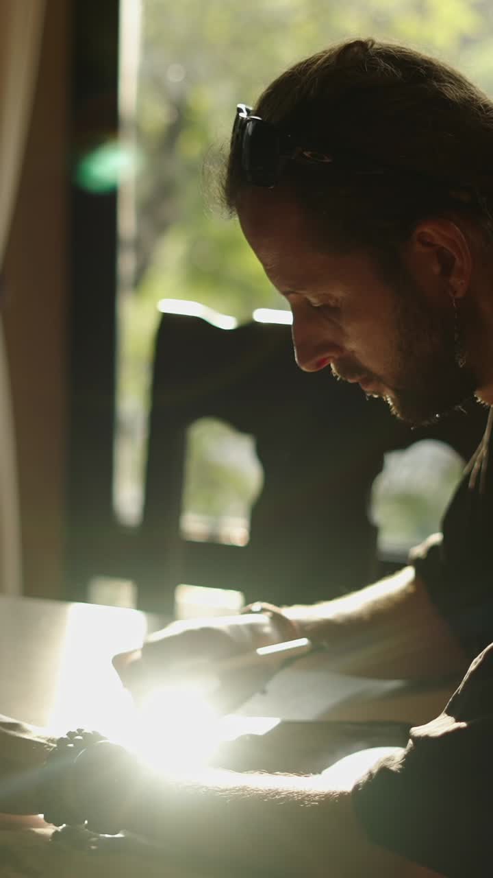 Artist drawing at a table by the window