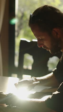 artist drawing at a table by the window