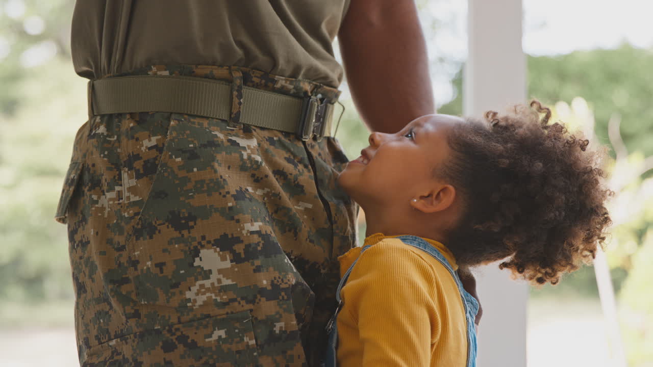 Nærbillede af kærlig militærfar i uniform, hjemme på orlov, krammer datter