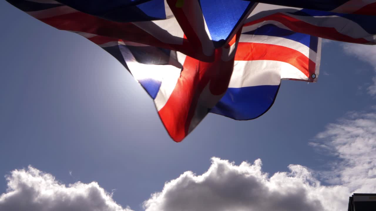 Union Jack British national flag flying against sunshine and clouds