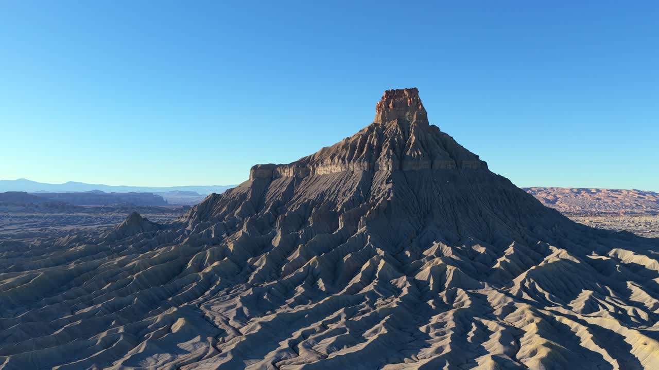 Une vue aérienne prise par un drone capture les vastes crêtes de schiste plissé des badlands de l’Utah. Ce terrain austère et d’un autre monde à Factory Butte crée une atmosphère surréaliste et cinématographique pour les médias de voyage.