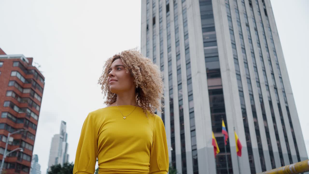 Câmera baixa acompanhando mulher caminhando em Bogotá, Colômbia, com torre.