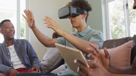 happy diverse male friends using vr headset and talking in living room