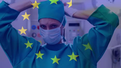 animation of flag of european union over caucasian female surgeon tying face mask