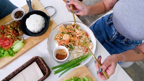 person eating pad thai with various side dishes