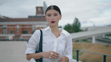 Businesswoman-walking-holding-coffee-takeaway-on-urban-street-close-up.