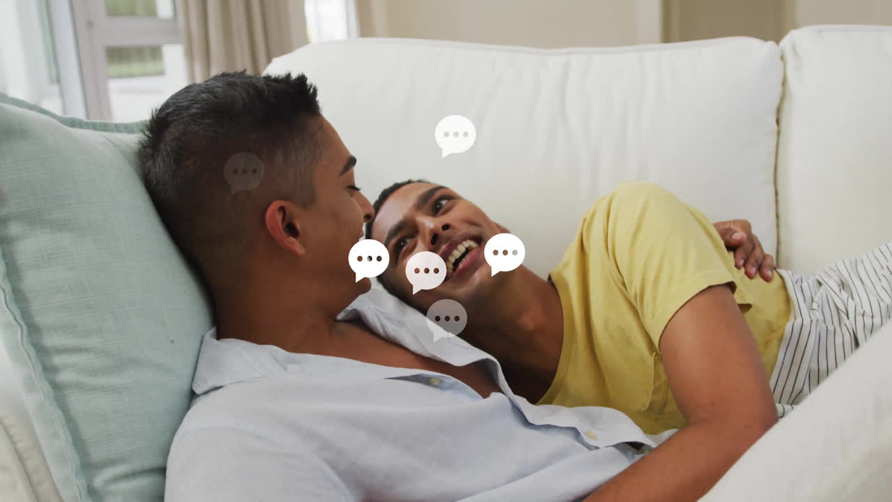 Two men lounging on sofa, viewing health app data with animated heart, chart icons