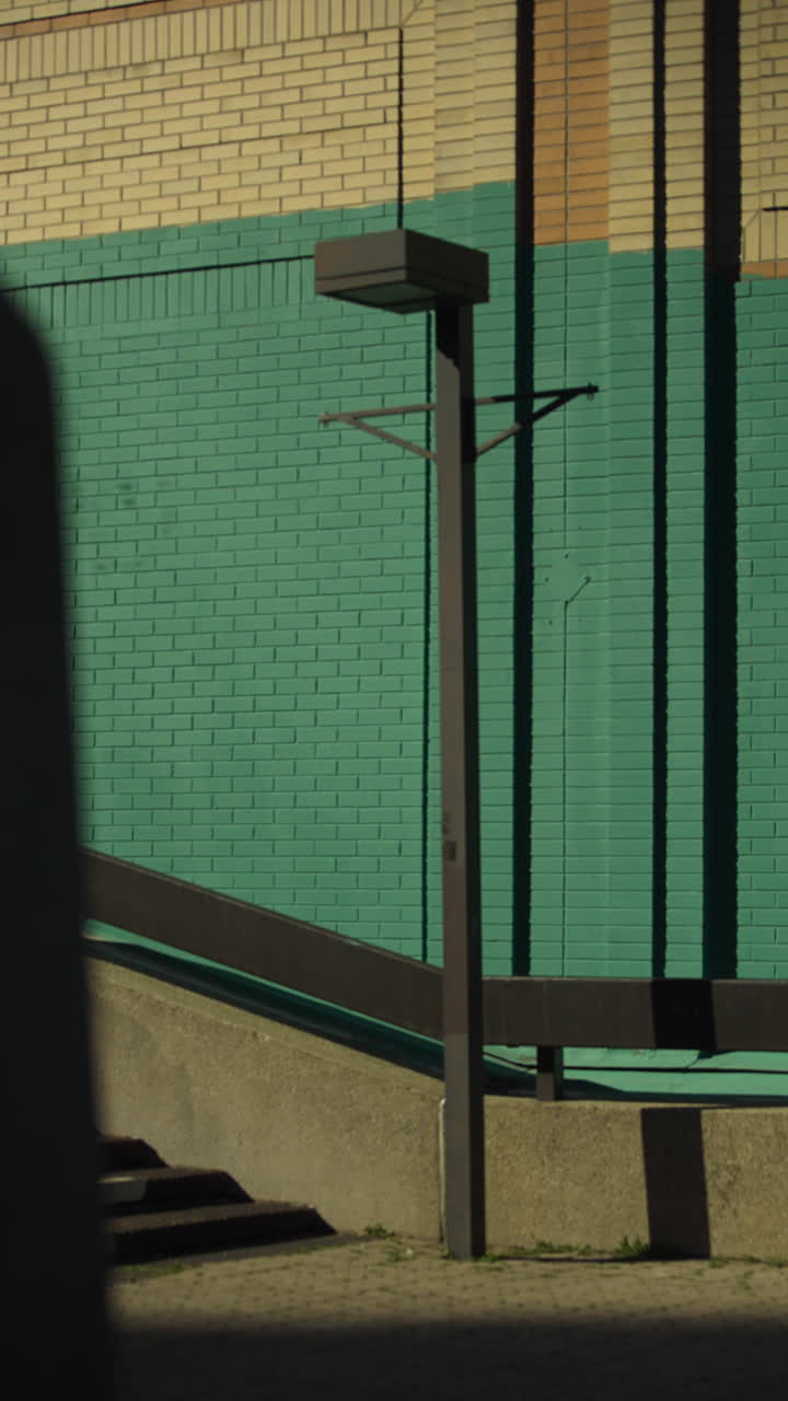 Teal And Beige Brick Wall With Modern Streetlight Casting Shadow On Sunny Day. vertical shot