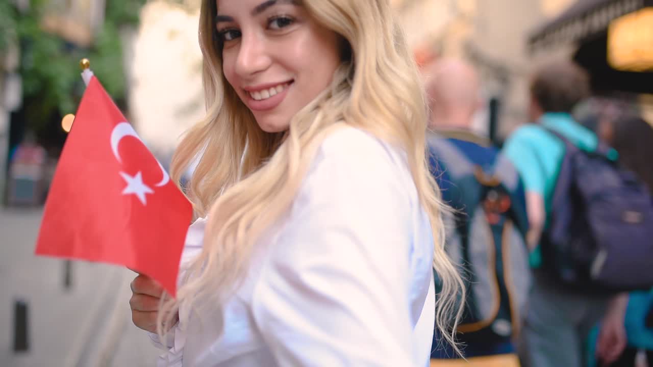 atractiva joven hermosa ondea la bandera turca y tira del brazo de su novio en una calle angosta en estambul, turquía