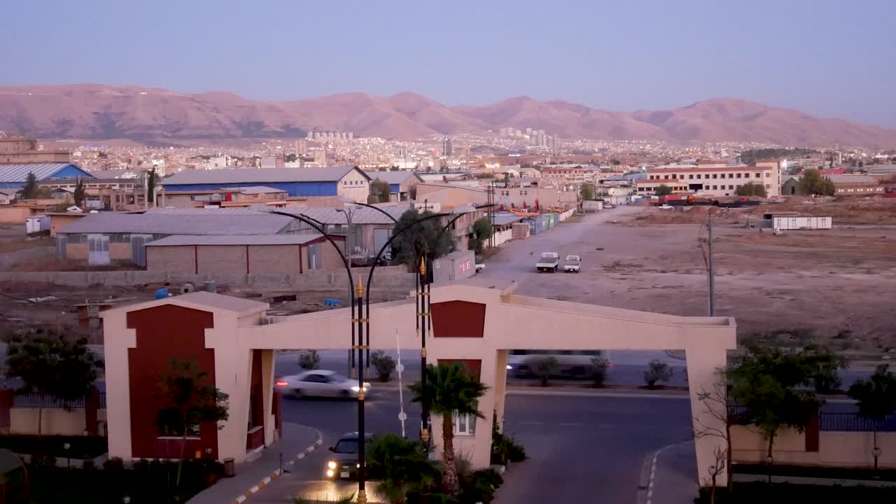 Cars traveling along a city road at dusk in Sulaymaniyah in Kurdistan Iraq - static shot