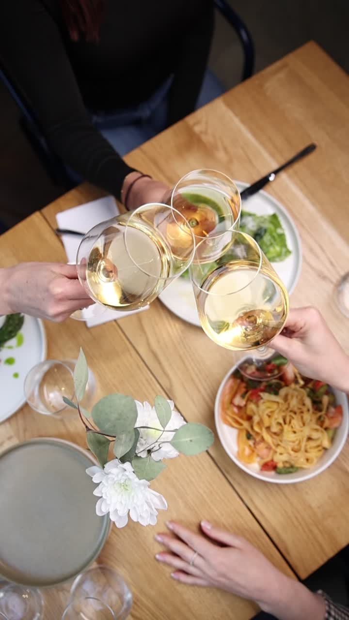 Friends Toasting with White Wine Glasses Over a Dining Table