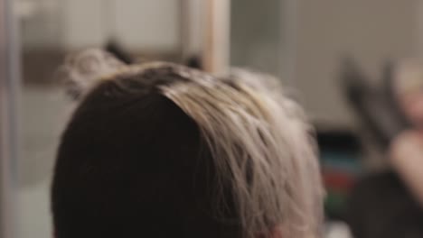 una mujer joven que blanquea el cabello mientras lo cepilla con los dedos - primer plano