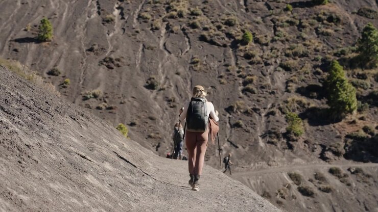 Hiker with trekking poles walking volcanic slope on Acatenango Volcano, Guatemala