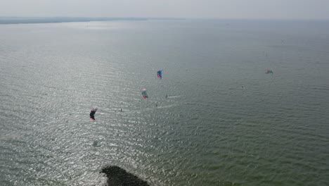 A-group-kitesurfers-at-Kornwerderzand,-Afsluitdijk-in-The-Netherlands,-drone-shot