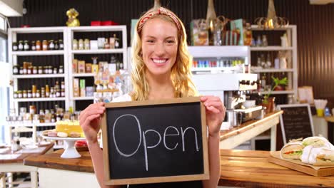 Smiling-waitress-showing-chalkboard-with-open-sign