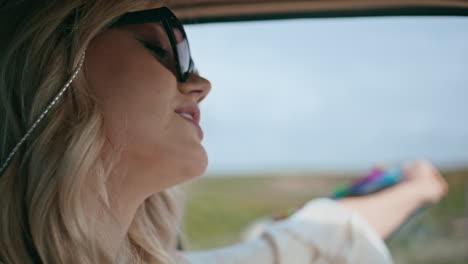 en primer plano, una conductora feliz sosteniendo una bufanda en el viento en la ventana abierta del coche. conducción rápida