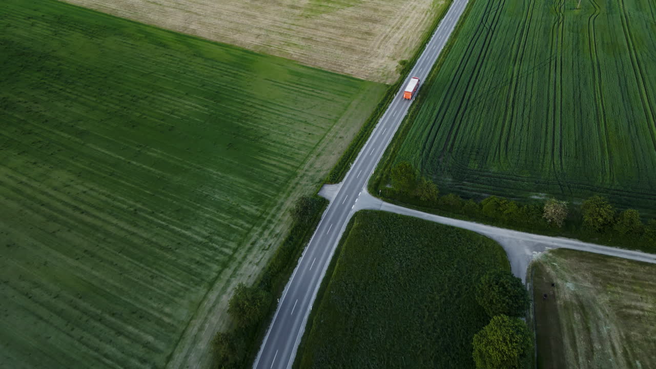 녹색 으로 둘러싸인 경치 좋은 독일 시골 도로를 가로질러 운전하는 트럭
