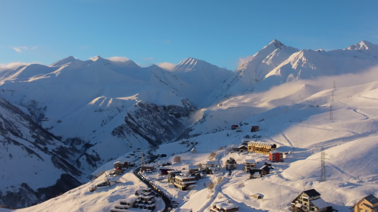 Riprese drone cinematografiche 4K che sorvolano Gudauri, rivelando le vaste vette del Caucaso che brillano alla calda luce dell'alba. Gudauri_068