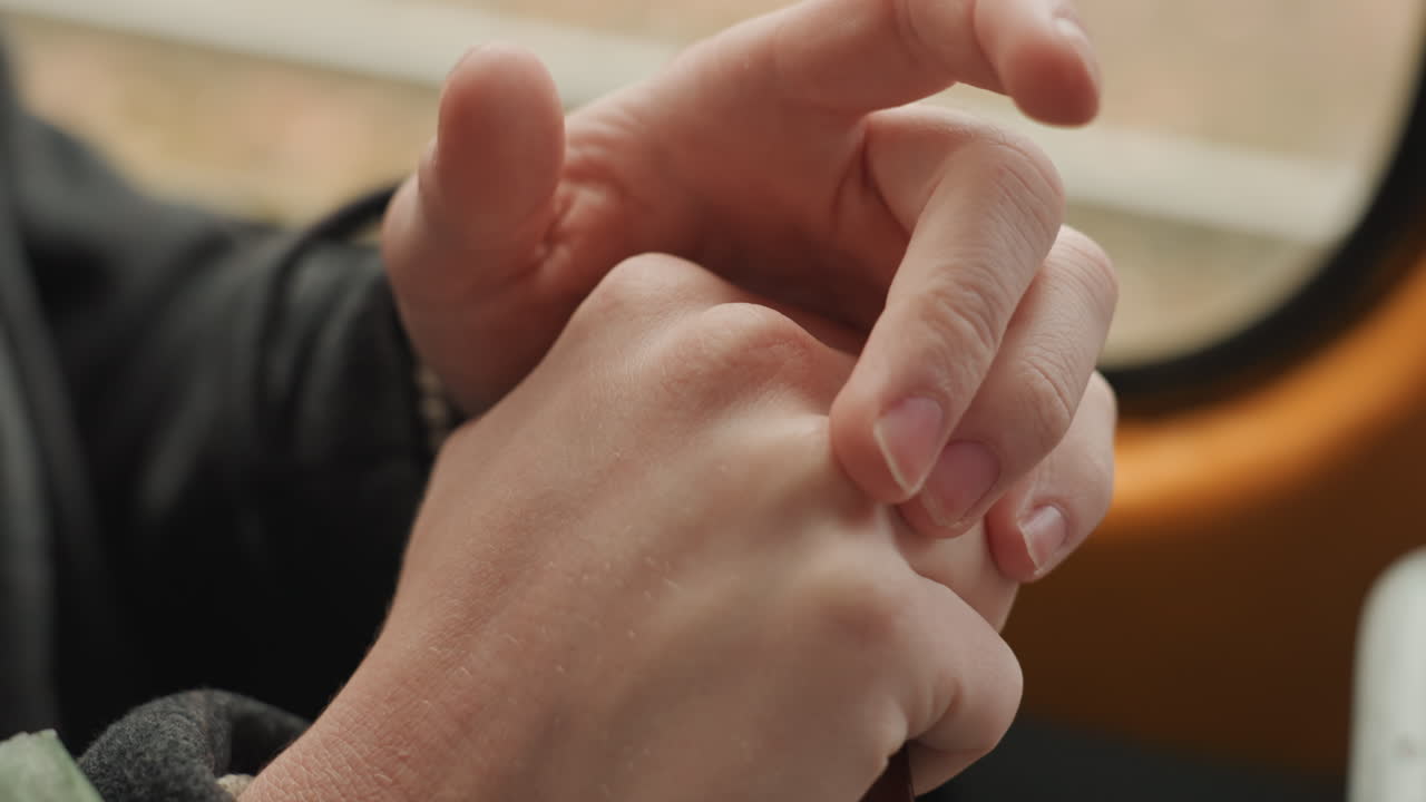 Hands fidgeting then gripping wooden handle, creator riding city bus, closeup of fingers and palm, textured wood and polished varnish, overcoat sleeve, steadying motion and quiet resolve