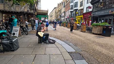 músico callejero tocando la guitarra en la concurrida calle oxford