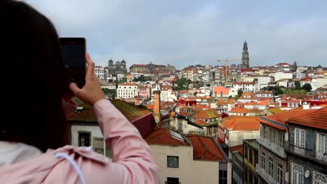 Woman-filming-Porto-landscape-from-lookout-with-her-smartphone-on-cloudy-day,-dolly-in