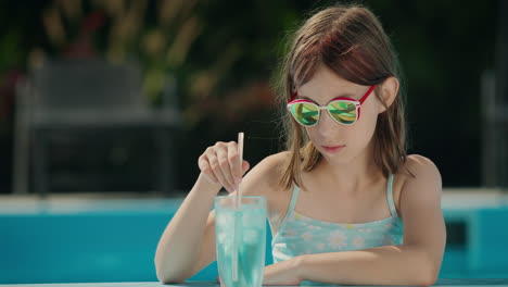 Teenage-girl-crushes-ice-in-a-cocktail-on-the-side-of-the-pool