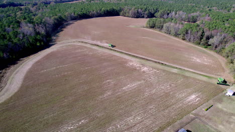 Drone-footage-of-soy-bean-harvesting-on-a-farm-field-with-a-harvester-or-tractor,-wide-rotating-aerial-shot