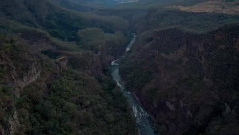 aerial-of-blue-river-within-a-mountain-valley-to-reveal-large-green-landscape-in-Michoacán-Mexico