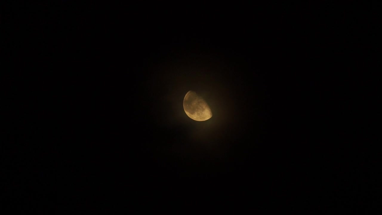 Nuvens passando lentamente em frente a uma lua brilhante à noite.