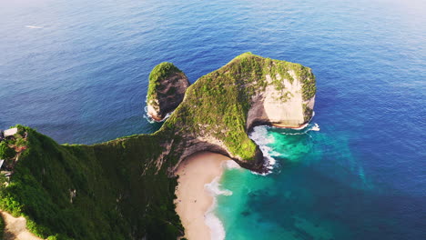 T-rex-beach-with-steep-ridge-with-green-foliage-above-blue-ocean-bay