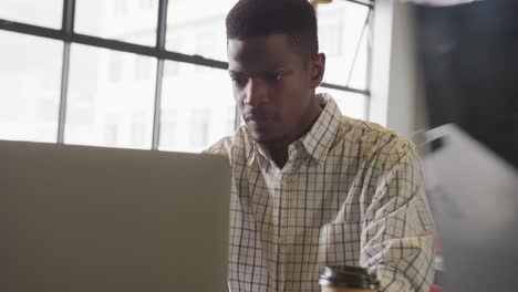 hombre de negocios afroamericano sentado en la mesa y usando una computadora portátil en la oficina