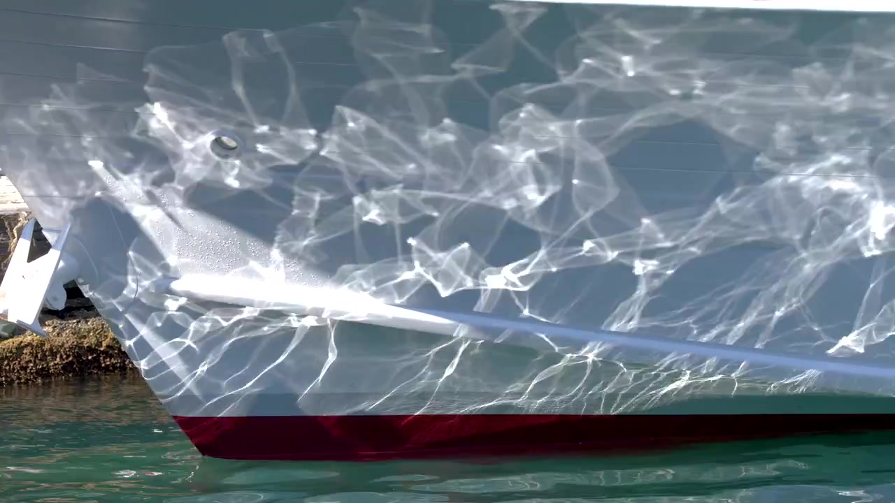 Riflessi della luce solare sullo scafo bianco di uno yacht ormeggiato.