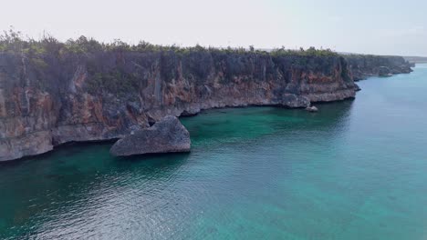 Acantilados-Escarpados-Y-Escarpados-Se-Elevan-Hacia-El-Agua-Azul-Turquesa-Durante-La-Puesta-De-Sol,-órbita-Aérea