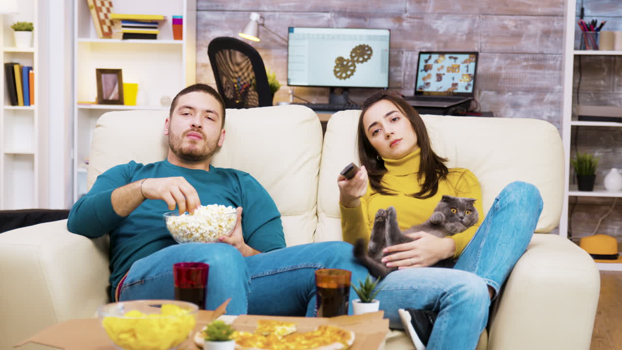 Couple Relaxing on Couch with Cat, Watching TV and Eating Popcorn