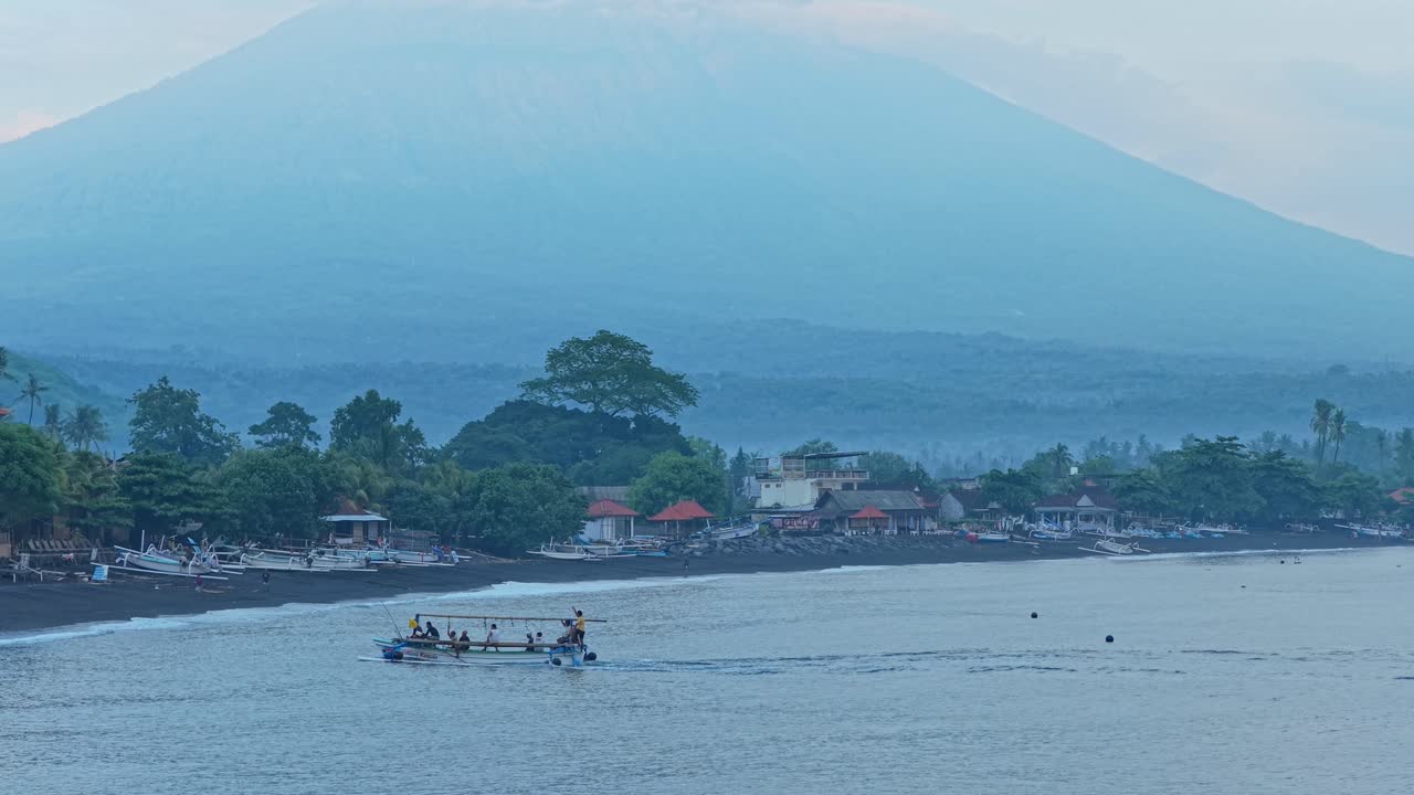 Traditional balinese jukung fishing boat sailing near mount agung volcano